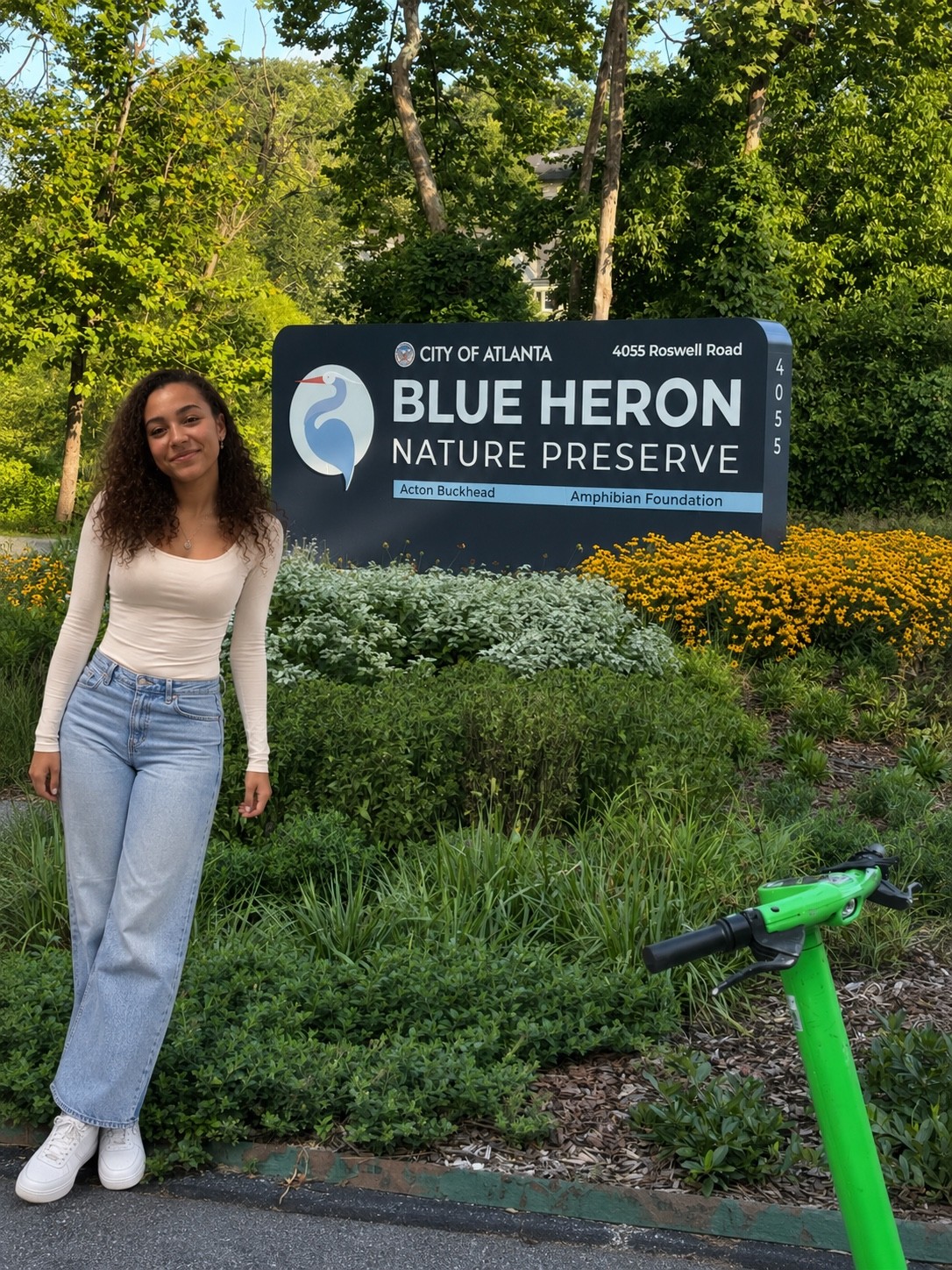 Visitor standing beside the Blue Heron Nature Preserve entrance sign in Atlanta
